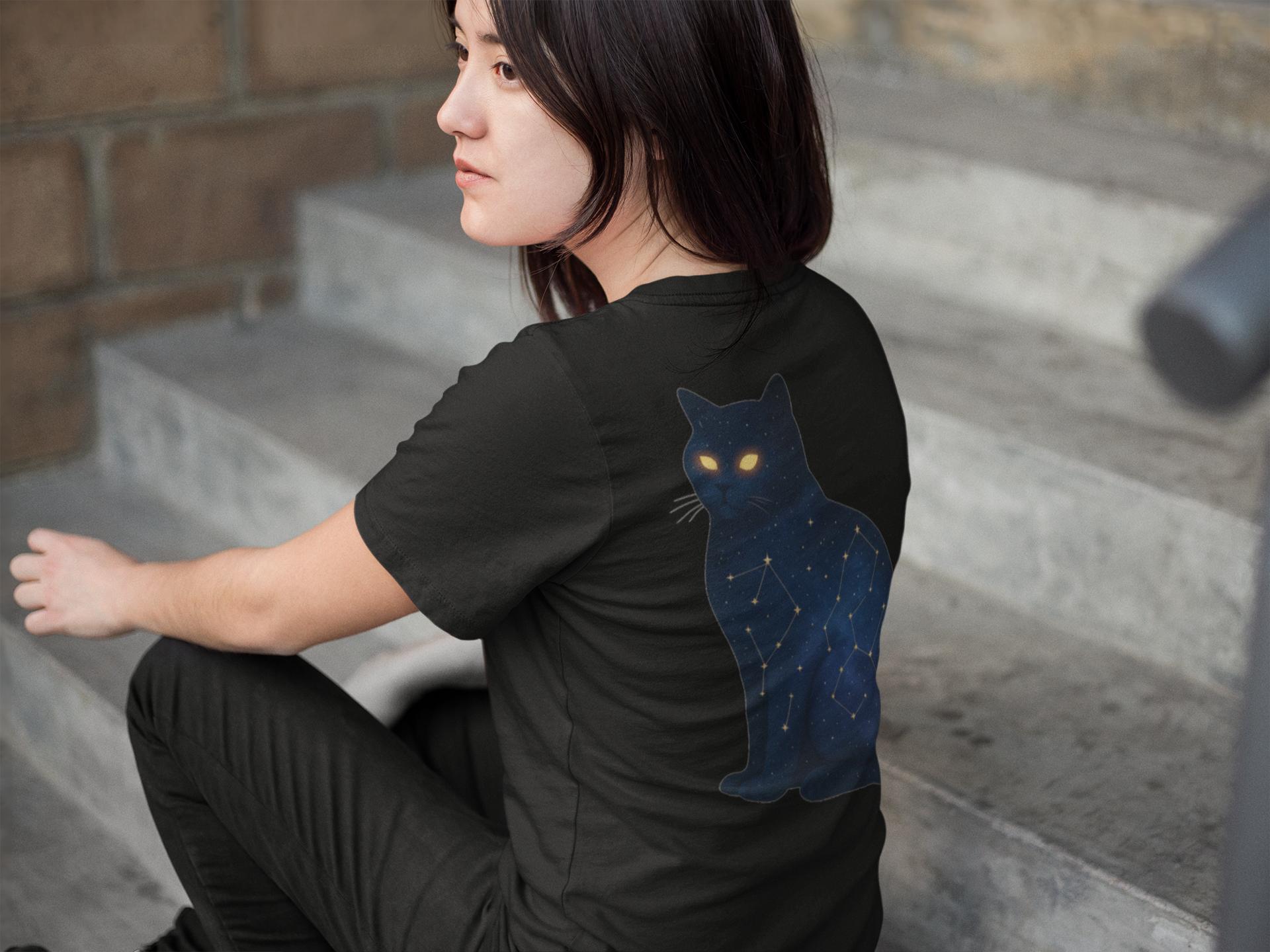 Woman wearing black t-shirt with cosmic cat print on back
