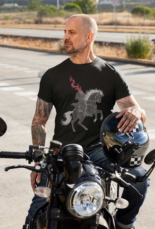 Tattooed man wearing black t-shirt with fire horse and headless horseman print sitting on motorcycle, holding helmet in hand
